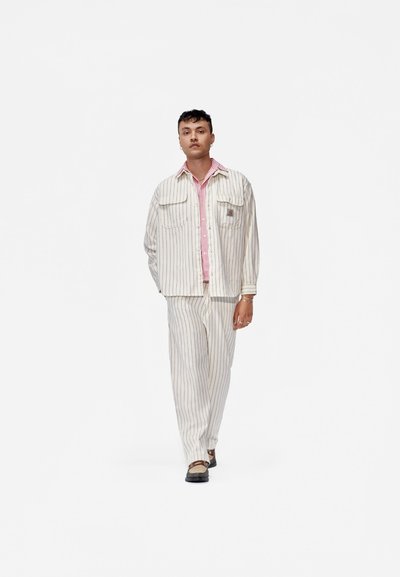 Conjunto de dos piezas a rayas beige que incluye una camisa de botones con cuello rosa y pantalones a juego, fabricado en tela ligera.