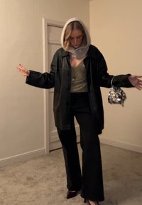 Veste noire en cuir oversize, débardeur vert ajusté à sequins, pantalon noir à jambes larges, sac à main argenté à sequins, et capuche gris pâle.