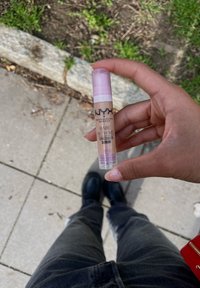 NYX Bare With Me Concealer Serum in un contenitore cilindrico; colore beige chiaro con tappo rosa; presenta il logo del marchio e i dettagli del prodotto sull'etichetta.