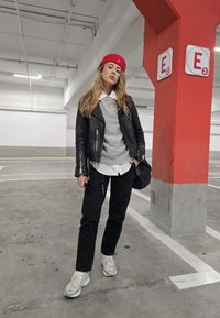 Δερμάτινο μπουφάν μηχανής πάνω από γκρι πουλόβερ, λευκό πουκάμισο, μαύρο παντελόνι και ασημένια sneakers. Το κόκκινο καπέλο και η μαύρη τσάντα προσθέτουν αντίθεση.