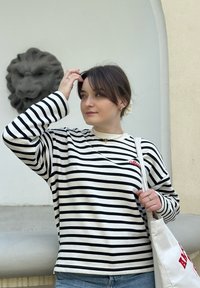 Μαύρη και λευκή ριγέ μπλούζα μακρυμάνικη με κόκκινες κεντημένες λεπτομέρειες, συνδυασμένη με ανοιχτό γαλάζιο τζιν και καμβά τσάντα. Λείος υφασμάτινος ιστός.