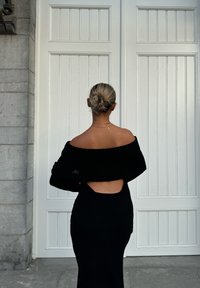 Zwarte gebreide jurk met een off-the-shoulder ontwerp en een uitsnede op de rug, met een geribbeld patroon en een aansluitende silhout.