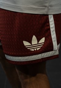Bordeaux atletiske shorts med et pustende mesh-materiale, med hvite sidestriper og en stor hvit Adidas trefoil-logo på venstre ben.