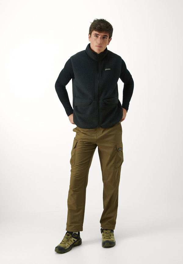 Chaleco de polar en gris oscuro con cremallera frontal y dos bolsillos delanteros, combinado con pantalones cargo en color caqui que presentan bolsillos laterales y un logo negro. Zapatos de gran resistencia.