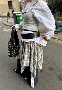 Szürke trikó világoskék csíkos ing alatt, fekete bőröv, kockás szoknya és szegecselt fekete táska. Vékony szabás különböző textúrákkal és mintákkal.