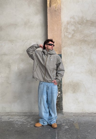 Chaqueta oversize a rayas en marrón y crema, combinada con vaqueros holgados azul claro, calzado marrón y gafas de sol negras. Tejido texturizado.