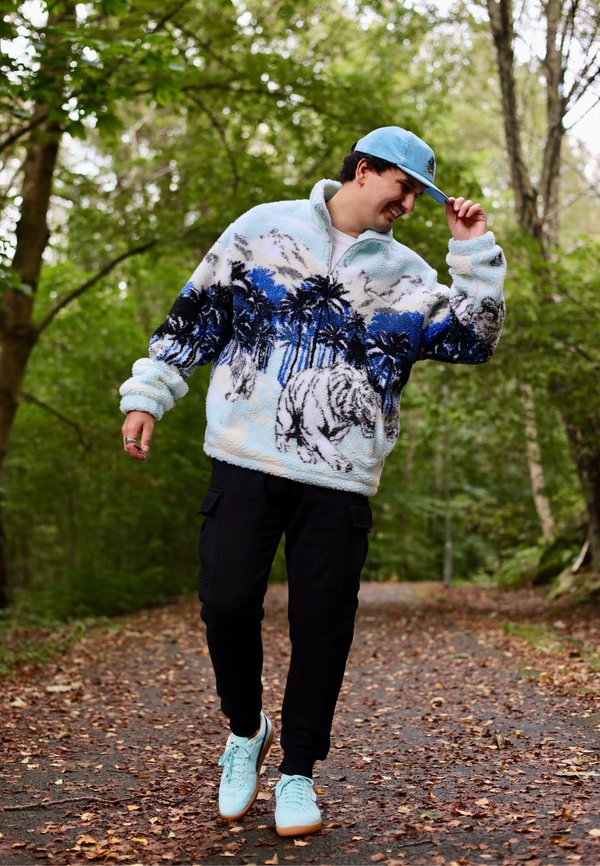 Fleece megztinis su šviesiai mėlynu pagrindu, juodais ir mėlynais delnų bei tigro raštais. Sukurtas kartu su juodomis cargo kelnėmis ir šviesiai mėlynais sportbačiais.
