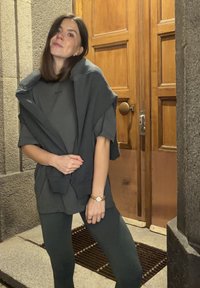 Sivi prevelik pulover, slojen čez ujemajočo se oprijeto majico in teksturirane legice; vsebuje preproste dizajne in minimalistično estetiko.