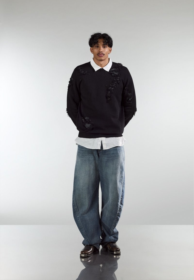 Must kampsun kulunud tekstuuriga, helehall kraega särk, lõdvad sinised teksad ja tumedad kingad. Minimalistlik disain, ilma mustrite või logodeta.