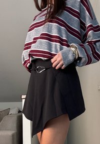 Sveternik sivi in maroon črtast, ohlapen kroj, v kombinaciji s črno krilo, ki ima elegantno srebrno zanko za pas in asimetrični rob.