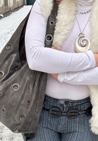 Sac en cuir gris avec de grandes découpes œillet, col roulé blanc, jean rayé bleu avec un détail unique de boucle noire, et un collier pendentif en spirale.
