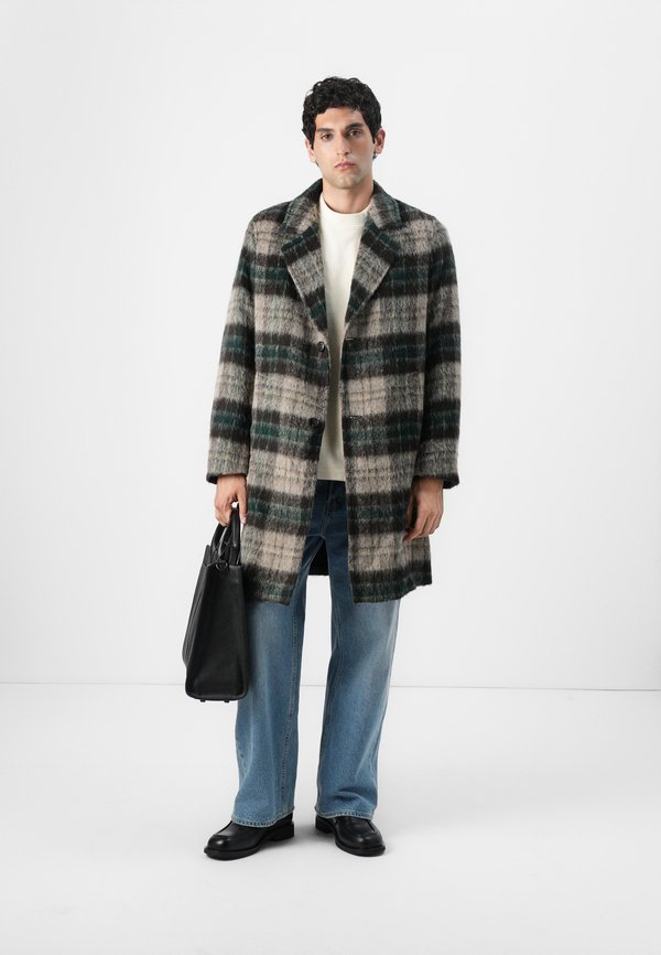 Wool plaid coat in grey, green, and black with a collar and button front, paired with a cream jumper, blue jeans, and black leather shoes.
