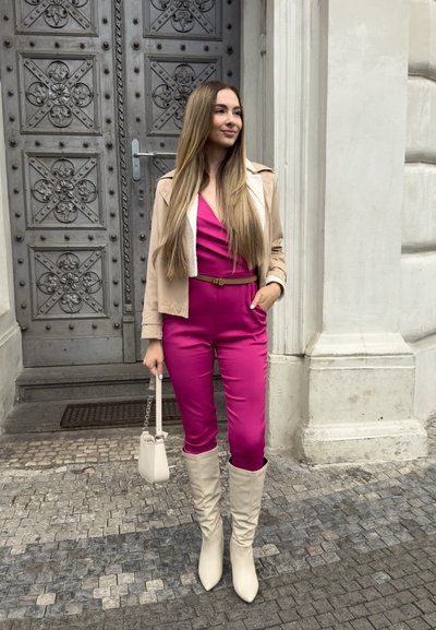 Mono rosa con cinturón en la cintura, chaqueta beige con forro de forro polar y botas color crema hasta la rodilla; llevando un pequeño bolso de mano crema.