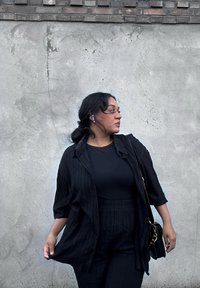 Svartstripet antrekk som består av en kortermet skjorte og matchende bukser laget av et teksturert stoff, kombinert med en svart veske og øreplugger.