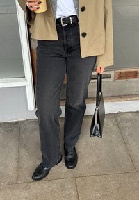 Beige jakke, grå sweater, hvid t-shirt, sorte høj taljede jeans, sorte loafers og en sort clutch. Ensfarvede farver, afslappet pasform.