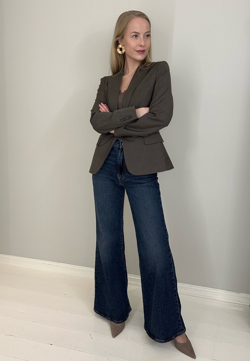 Blazer marron sur mesure porté sur un débardeur foncé, associé à un jean denim foncé à jambes larges et des talons pointus beige. Grandes boucles d'oreilles en or circulaires.