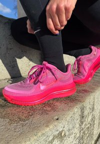 Roosad spordijalatsid, millel on tekstureeritud võrgust pealmine osa, kummist talla ning erkroosa vahtpõhi. Paelad ja Nike logo sobivas roosas toonis.