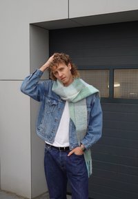 Veste en denim portée sur un t-shirt blanc, associée à un jean bleu foncé et à une écharpe vert menthe clair, avec une texture douce et des variations de couleur subtiles.