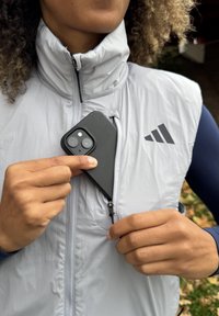 Gai pelēks ar rāvējslēdzēju jaciņvēsture ar augstu apkakli, kurā ir maza kabata melnajai telefona. Strukturēta auduma ar sportisku dizainu un logo akcentu.