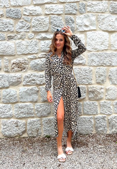 Vestido maxi de estampado de leopardo con mangas largas, botones en el frente y abertura alta en el muslo. Tejido ligero y cintura ceñida. Combinado con sandalias planas.
