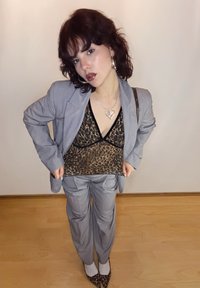 Blazer gris par-dessus un haut imprimé léopard noir, associé à un pantalon gris et des escarpins imprimés léopard. Des accessoires métalliques viennent accentuer la tenue.