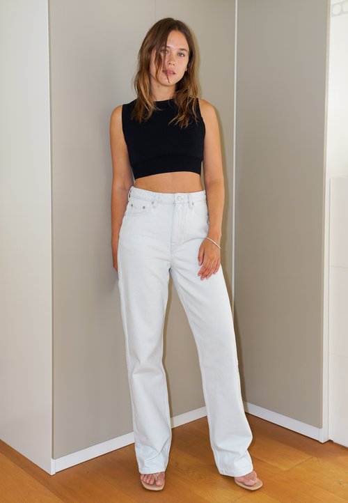 Ylipitkä laivaston sininen neule, tummat shortsit, mustat polvipituiset saappaat ja ruskea laukku, jossa on solmittu kahva. Sujuvat tekstuurit ja moderni siluetti.