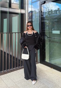 Sort off-shoulder top med hvide detaljer, sorte brede bukser, jakke med faux pels, hvid håndtaske, solbriller og spidse hvide hæle.