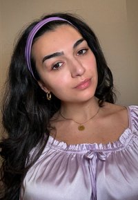 Lavendelfärgad satinblus med rynkad halsringning, bärs med ett guldhalsband som har en cirkulär berlock och ett lila hårband.