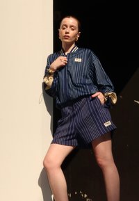 Blåstripet skjorte med kremfargede detaljer, kombinert med matchende shorts. Inkluderer Fila-logo. Glatt materiale med avslappet passform og oppbrettede ermer.