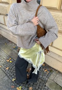 Grey ribbed turtleneck jumper, layered over a yellow satin skirt with lace trim. Paired with dark pinstriped wide-leg trousers and a brown fringe bag.