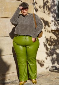 Γκρι πλεκτό πουλόβερ, γυαλιστερά πράσινα δερμάτινα παντελόνια και χρυσά παπούτσια. Το συνοδευτικό στοιχείο της εμφάνισης είναι ένα γκρι καπέλο και μια καφέ τσάντα ώμου.