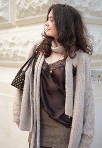 Brown satin camisole with lace trim, layered under a light gray knitted cardigan, paired with a brown herringbone skirt and a small black handbag.