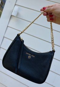 Svart teksturert lærveske med gullkjedestropp. Har glidelåslukking og gull-logo detaljer på forsiden.