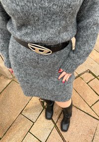 Robe grise en maille à manches longues, ceinture noire avec boucle ovale argentée, et bottes noires montantes jusqu'aux genoux. Surface texturée avec motif côtelé.