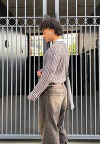 Grey ribbed sweater, loose-fitting dark jeans, and a grey shoulder bag. The outfit showcases a relaxed design with visible textures and stitching.