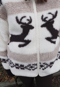 Flis jakna z zadrgo spredaj, s potiskom severnega jelena v temno rjavi barvi na kremasti in svetlo rjavi črtasti podlagi.