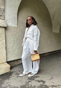 Camicia bianca a righe e pantaloni abbinati, abbinati a ballerine con pois e una piccola borsa di vimini.