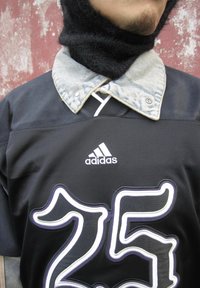 Czarny sportowy strój z białą i fioletową obramówką "25", logo Adidas oraz dżinsowym kołnierzem nad czarnym dzianinowym kominem na szyję.