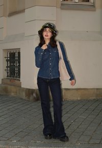 Τζάκετ από ντένιμ με κουμπιά, συνδυασμένο με σκούρες φαρδιές τζιν και ένα πολύχρωμο πλεκτό καπέλο τύπου bucket. Μια καμβά τσάντα κομμένη στο χέρι.