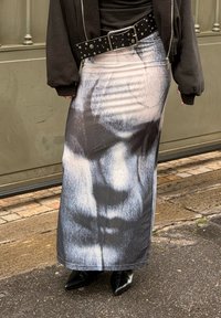 Schwarz-weißer langer Rock mit abstraktem Print, aus glattem Stoff, mit hoher Taille und leichtem Glanz. Schwarzer Gürtel mit Nieten.