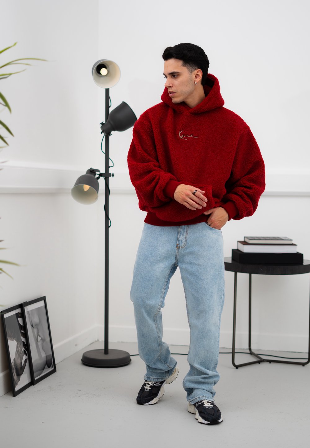 Κόκκινο φλις φούτερ με υφασμάτινη υφή, χαλαρή εφαρμογή και κεντητές λεπτομέρειες. Συνδυάζεται με ανοιχτό μπλε τζιν και μαύρα αθλητικά παπούτσια.