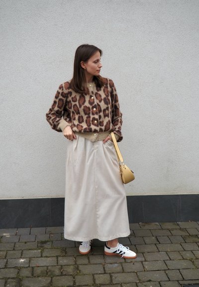 Cárdigan de estampado de leopardo en tonos marrón oscuro y beige, con botones dorados, combinado con una falda maxi beige clara y zapatillas blancas con detalles en beige.