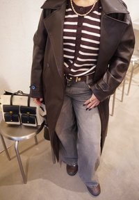 Barna bőr ballonkabát barna-fehér csíkos pulóverrel, szürke bőszárú farmernadrággal és barna csizmával párosítva. Tartozik hozzá egy krémszínű táska fekete díszítéssel.