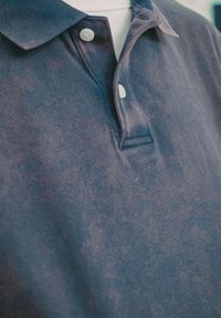 Marineblå bomulls polo med teksturert overflate, treknappers lukking og klassisk krage.