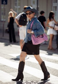 Τζιν πουκάμισο, μαύρες σορτς, μαύρες καουμπόικες μπότες και μωβ τσάντα. Αξεσουάρ περιλαμβάνουν γυαλιά ηλίου και ρολόι χειρός. Σκηνικό δρόμου.