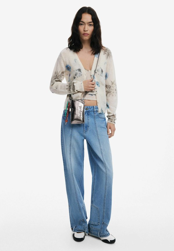 Blommönstrad oversized cardigan i gräddvit, med blå blommor. Ljusblå vida jeans, tillsammans med svart och vit skor samt en silverfärgad axelväska.