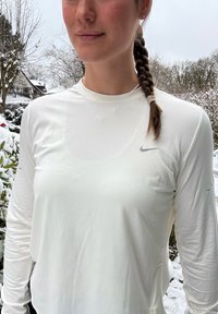 T-shirt à manches longues Nike en tissu blanc, arborant un logo gris subtil sur le côté supérieur gauche, texture lisse et coupe décontractée.