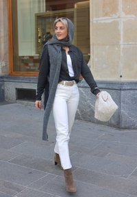 Grijs overhemd met knopen, wit tanktopje, witte spijkerbroek, beige enkellaarsjes, grijze sjaal en een donzige beige handtas. Soepele texturen, neutrale kleuren.