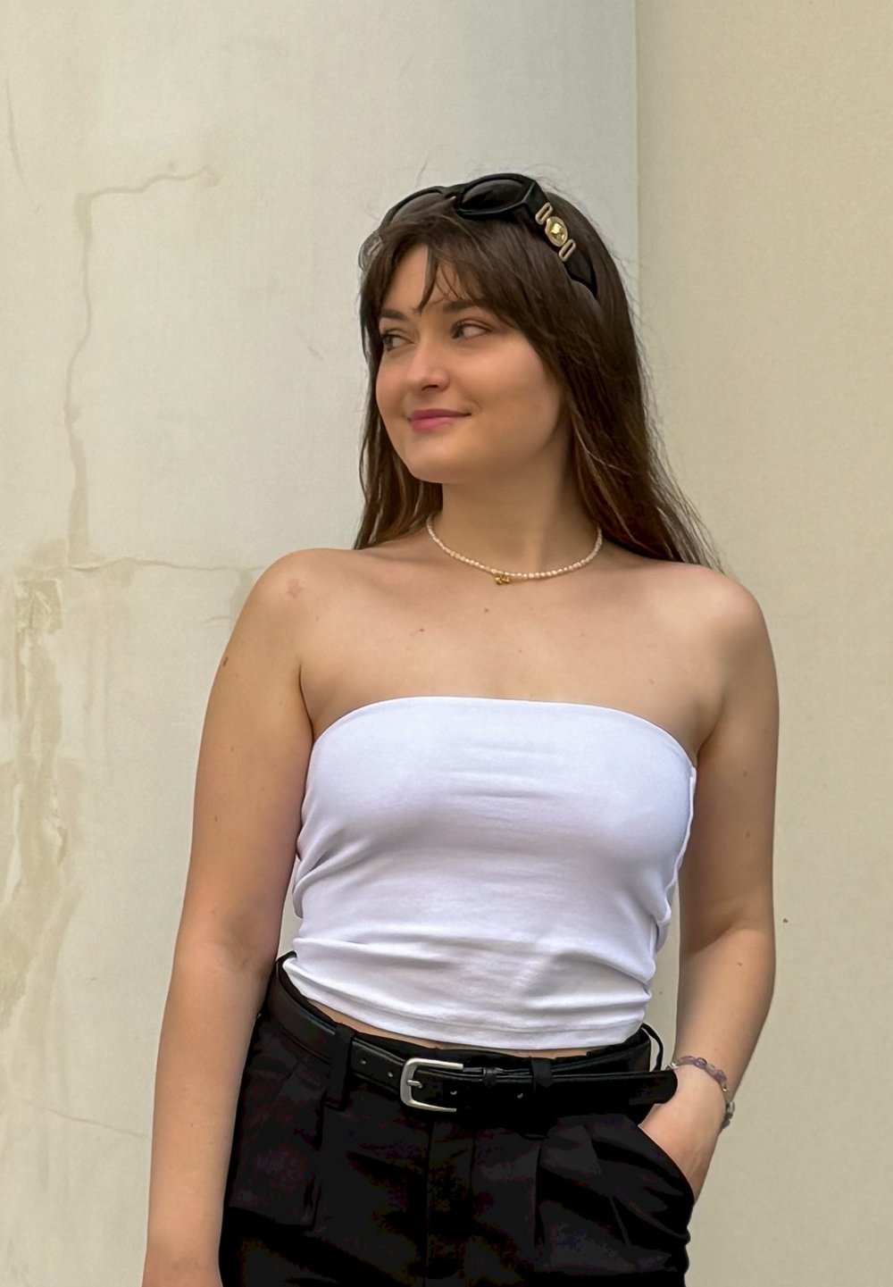 Λευκή τοπ χωρίς straps, μαύρα παντελόνια ψηλής μέσης και μια μαργαριταρένια κολιέ. Μαύρη κορδέλα για τα μαλλιά και γυαλιά ηλίου. Λείος υφής, casual στυλ.