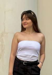 Λευκή τοπ χωρίς straps, μαύρα παντελόνια ψηλής μέσης και μια μαργαριταρένια κολιέ. Μαύρη κορδέλα για τα μαλλιά και γυαλιά ηλίου. Λείος υφής, casual στυλ.